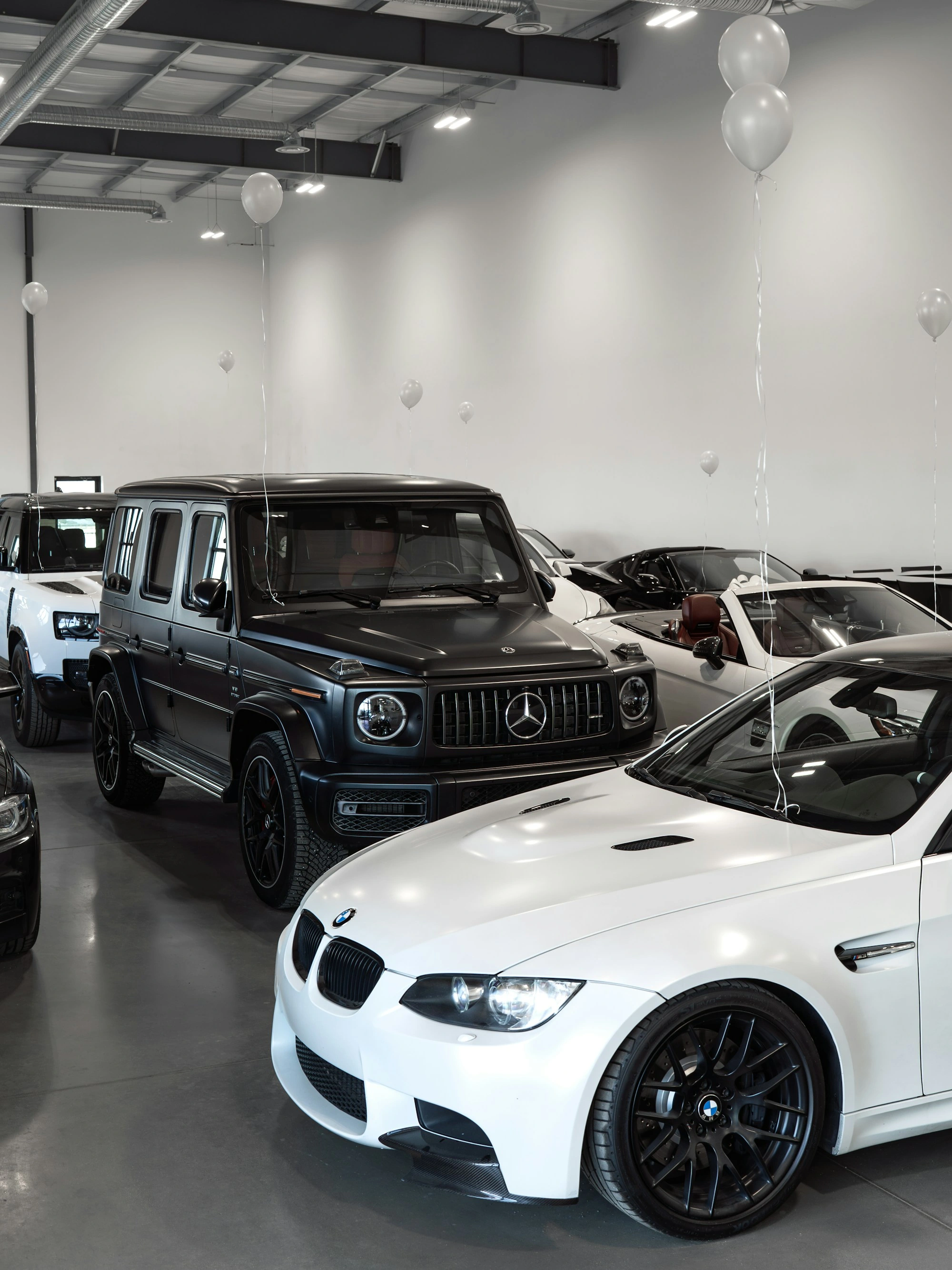 Vehicles arranged in a showroom decorated with white balloons