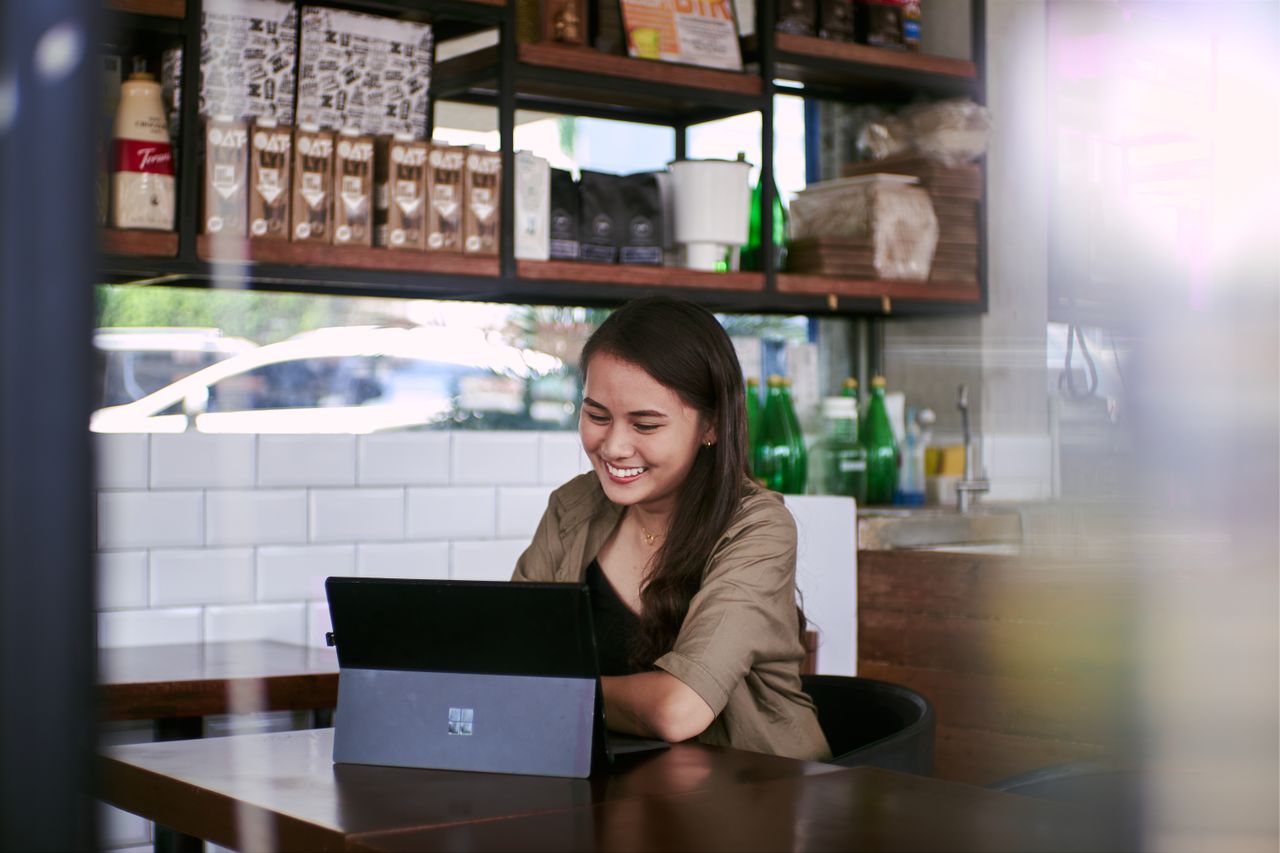 A customer smiling at her laptop in a bright cafe