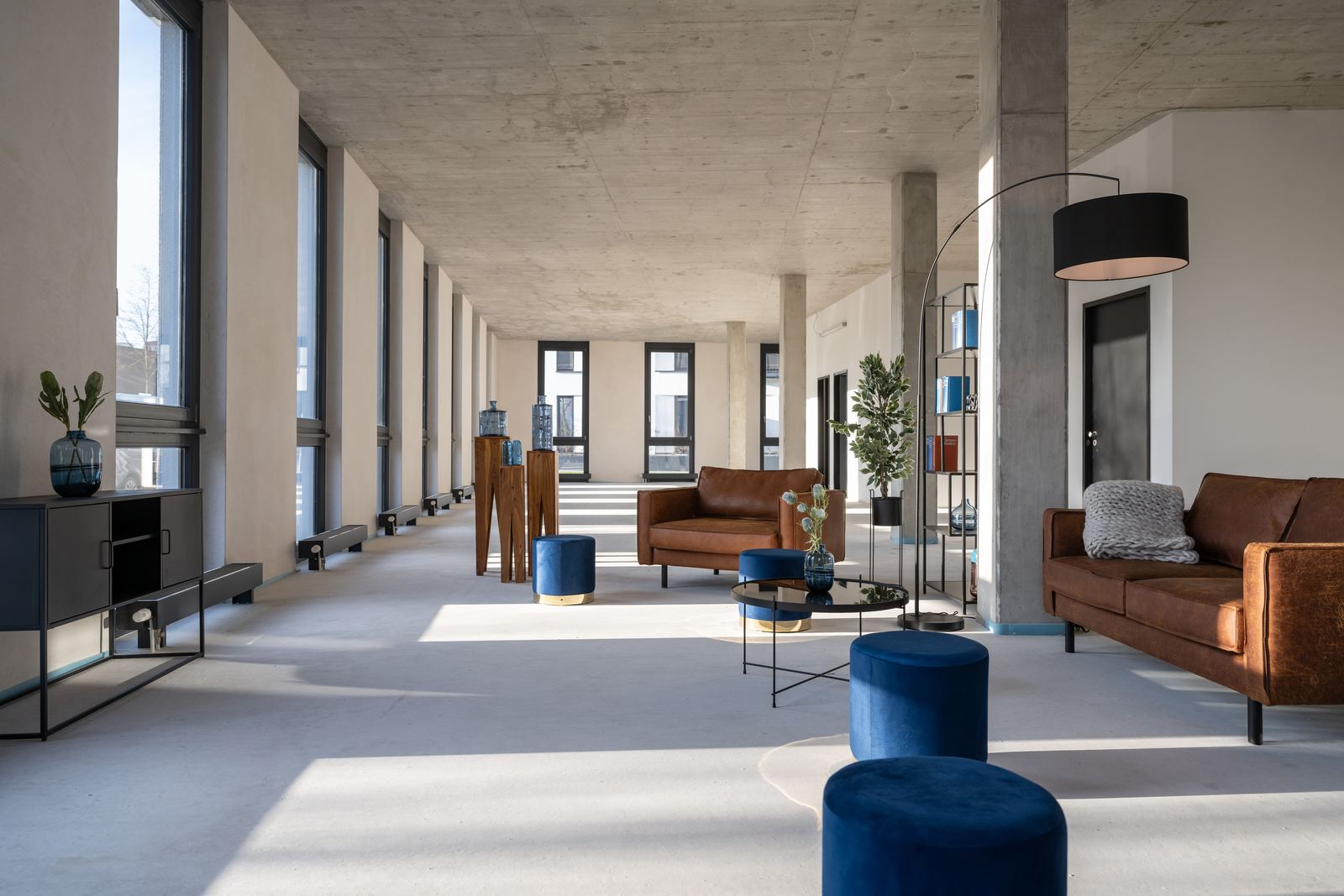 Lounge im Erdgeschoss mit Sichtbetondecke und raumhohen Fenstern