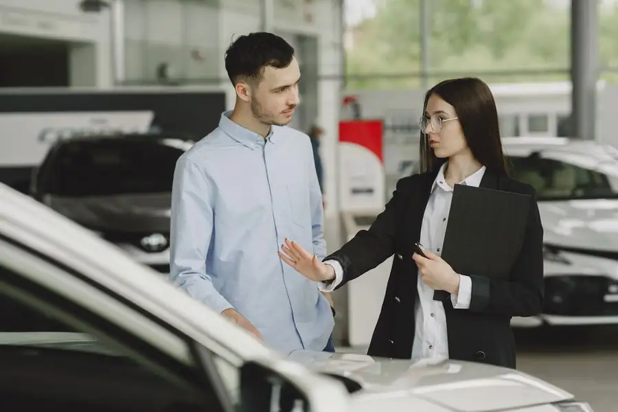 Vendedora atendiendo a un cliente en un concesionario de autos