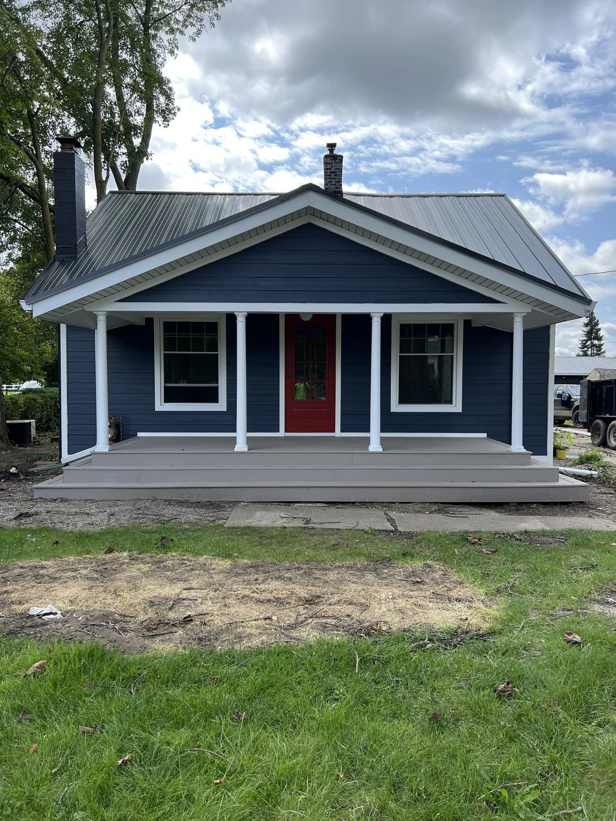 Blue home exterior with a red front door and a covered front porch