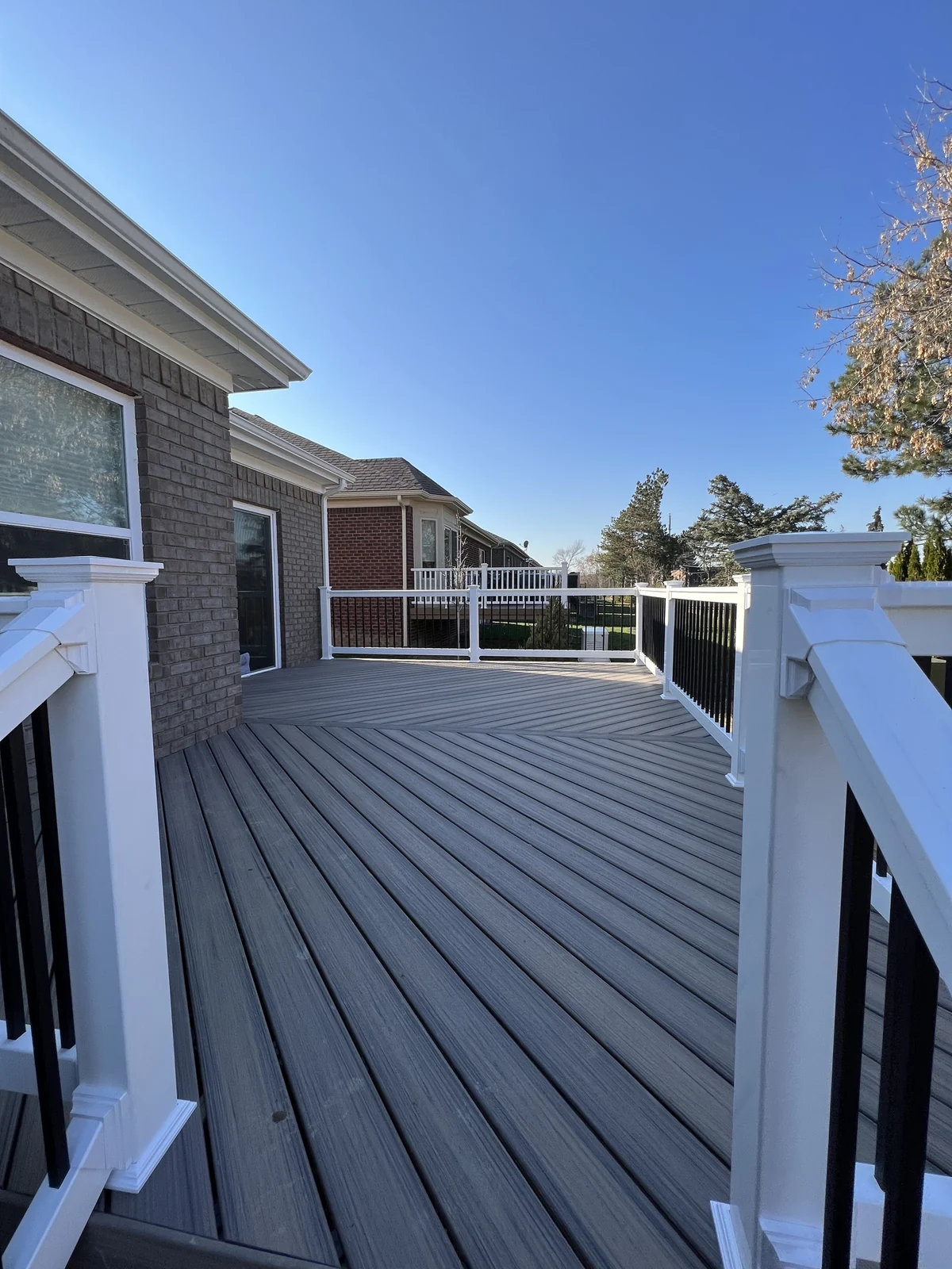Gray composite deck with white railings beside a home