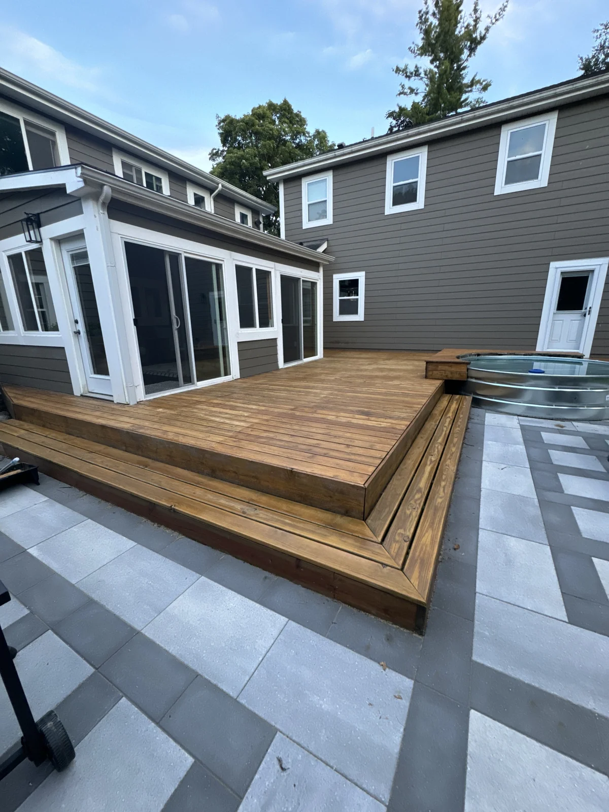 Wood deck with wide steps opening onto a stone patio