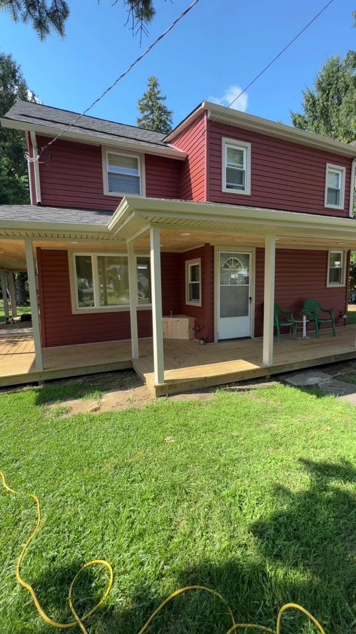 Red two-story home with porch roof and posts in place before railings are installed