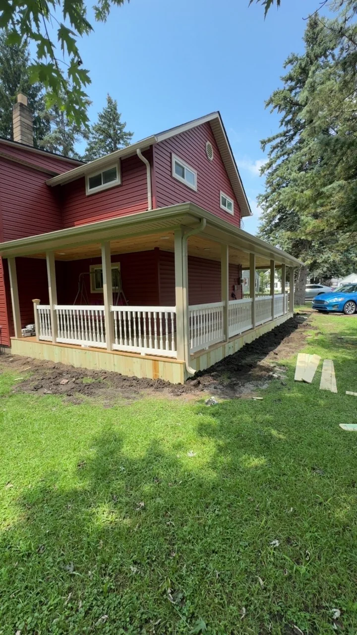 White railings and a wood skirt along the side of the wraparound front porch
