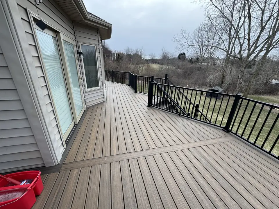Gray composite deck with black railings beside sliding patio doors