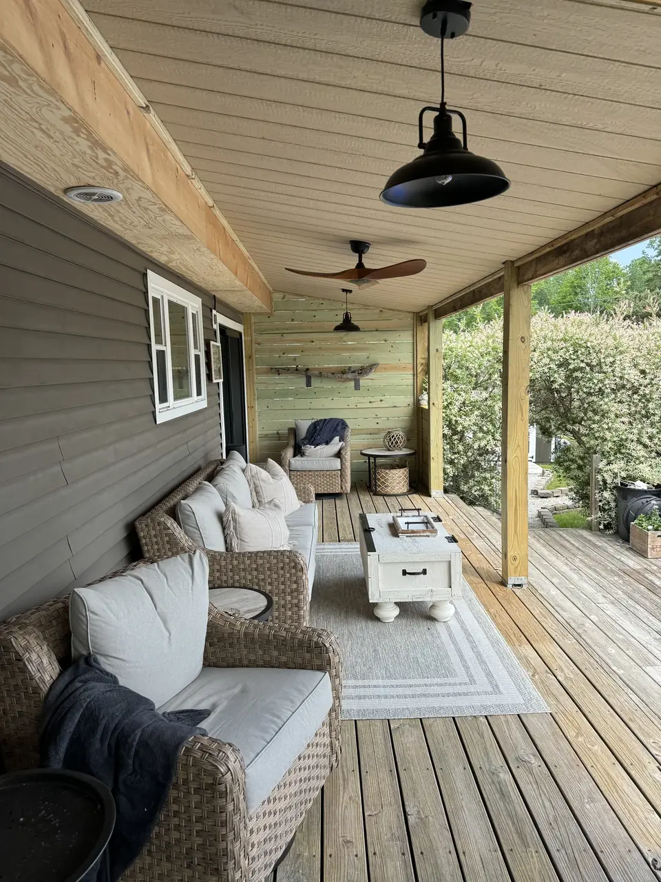 Covered wood porch with wicker seating, timber posts and pendant lights