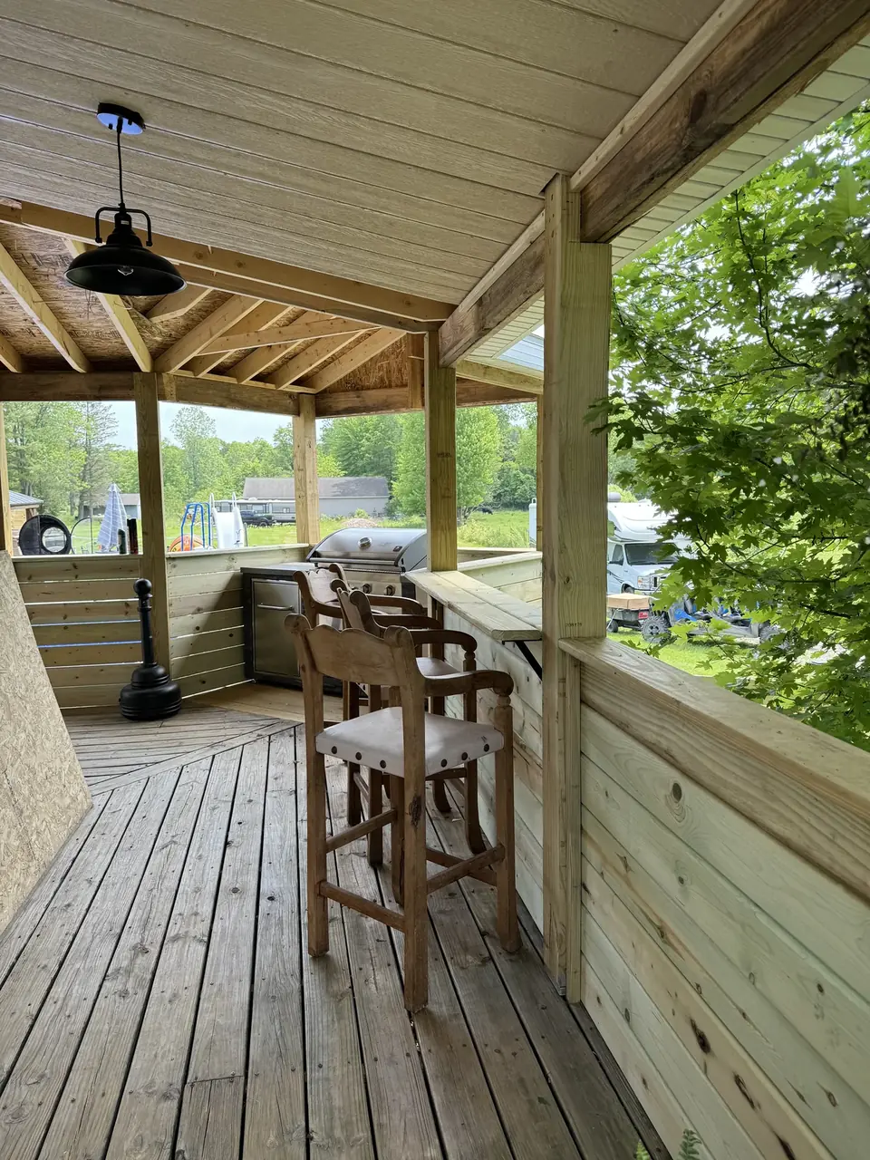 Covered deck with a wood bar counter, timber framing and a grill
