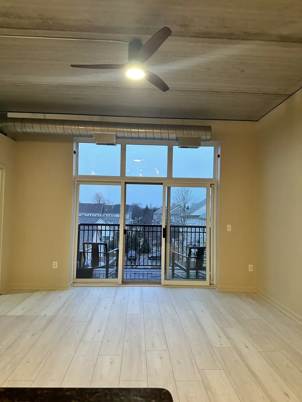 Interior room with pale flooring, a ceiling fan and large glass doors to a balcony