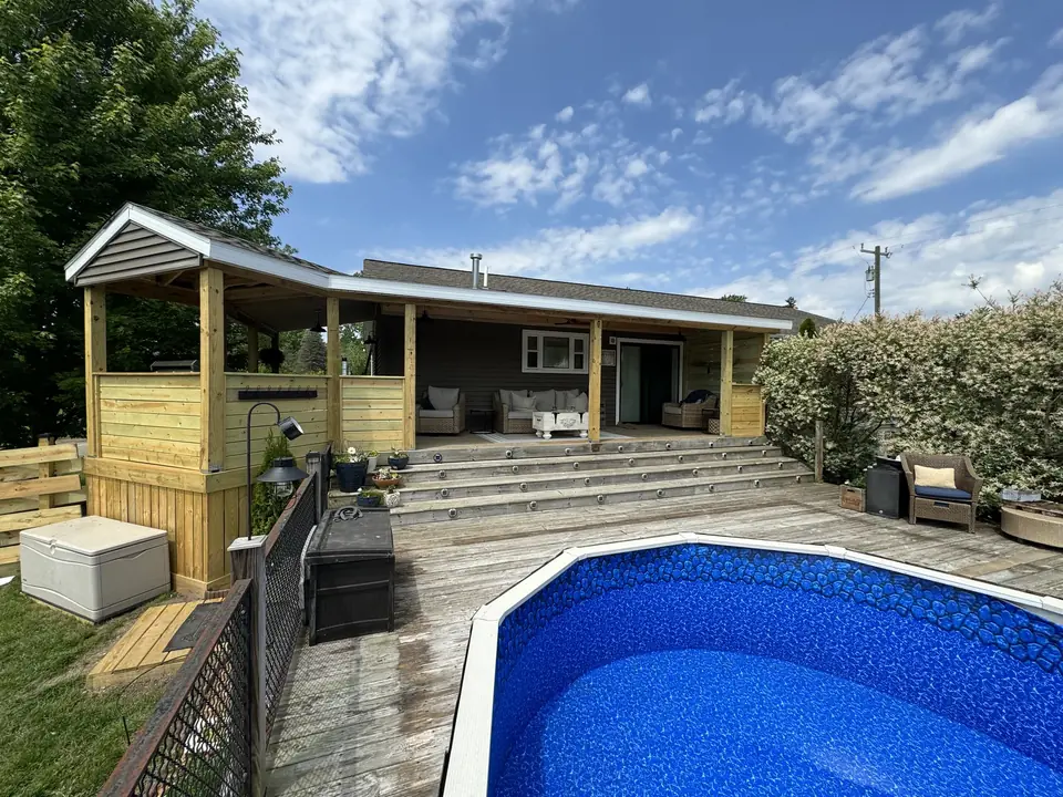 Covered wood porch and broad steps beside an above-ground pool