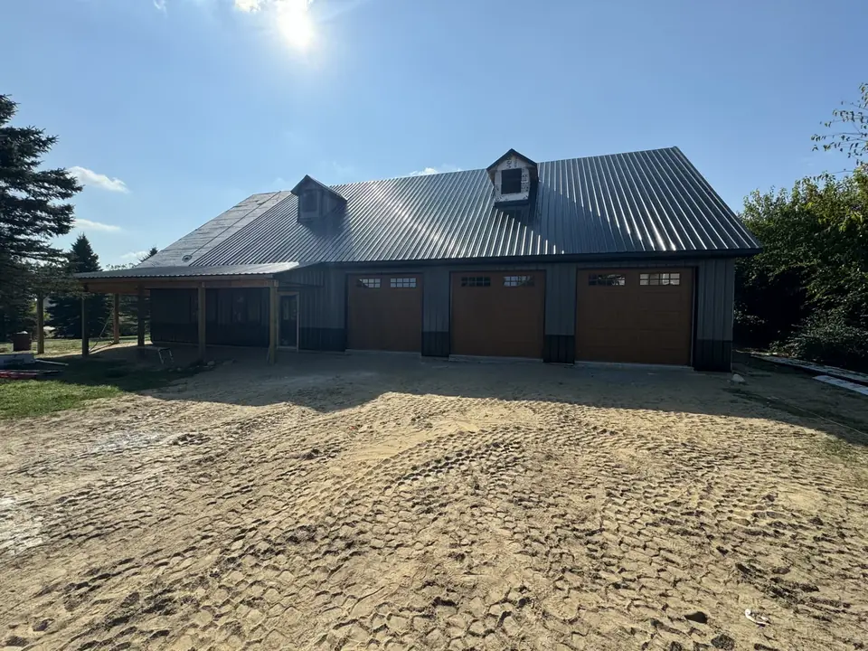 Three-bay garage with a metal roof and covered side area during construction