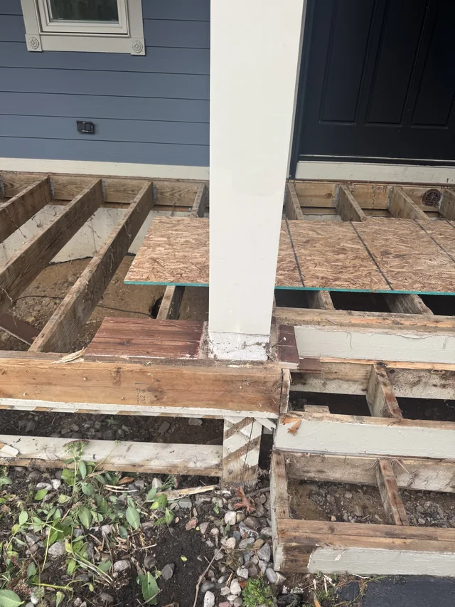 Exposed porch framing beside blue siding and white columns
