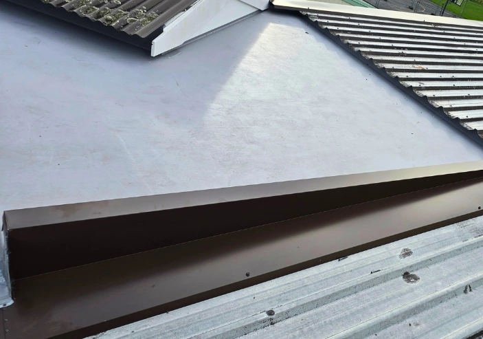 Roof repair work fixing leaks and damaged flashings on a metal roof