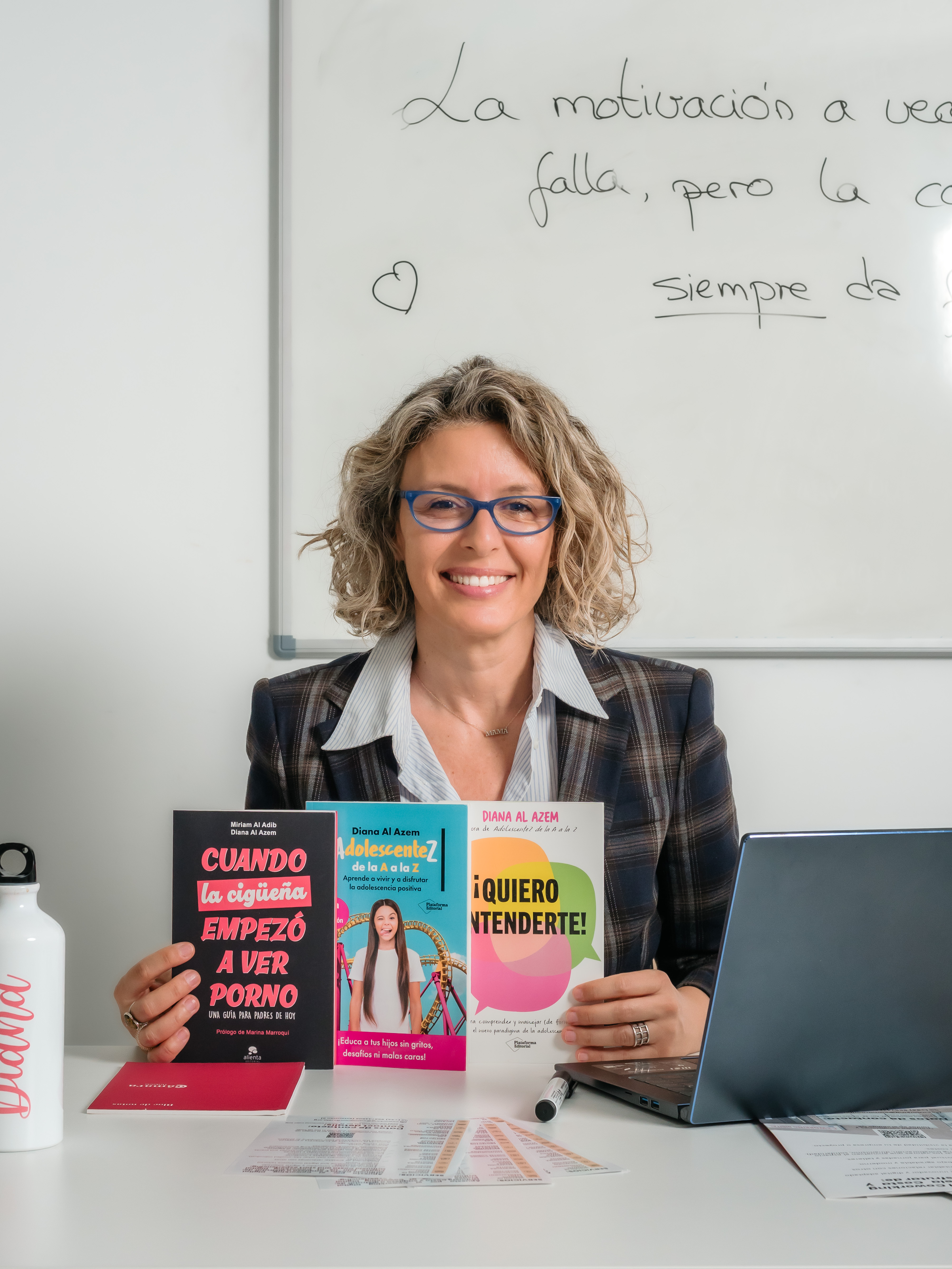 Diana Al Azem sentada en su mesa de trabajo sosteniendo sus libros sobre adolescencia