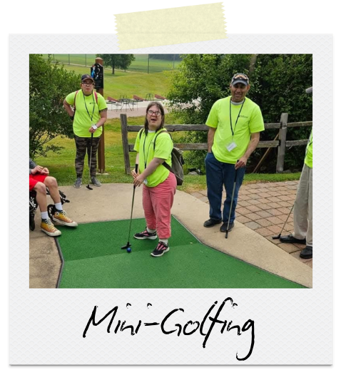 Mini-golfing: Three individuals in neon green shirts stand around mini-golf green smiling.