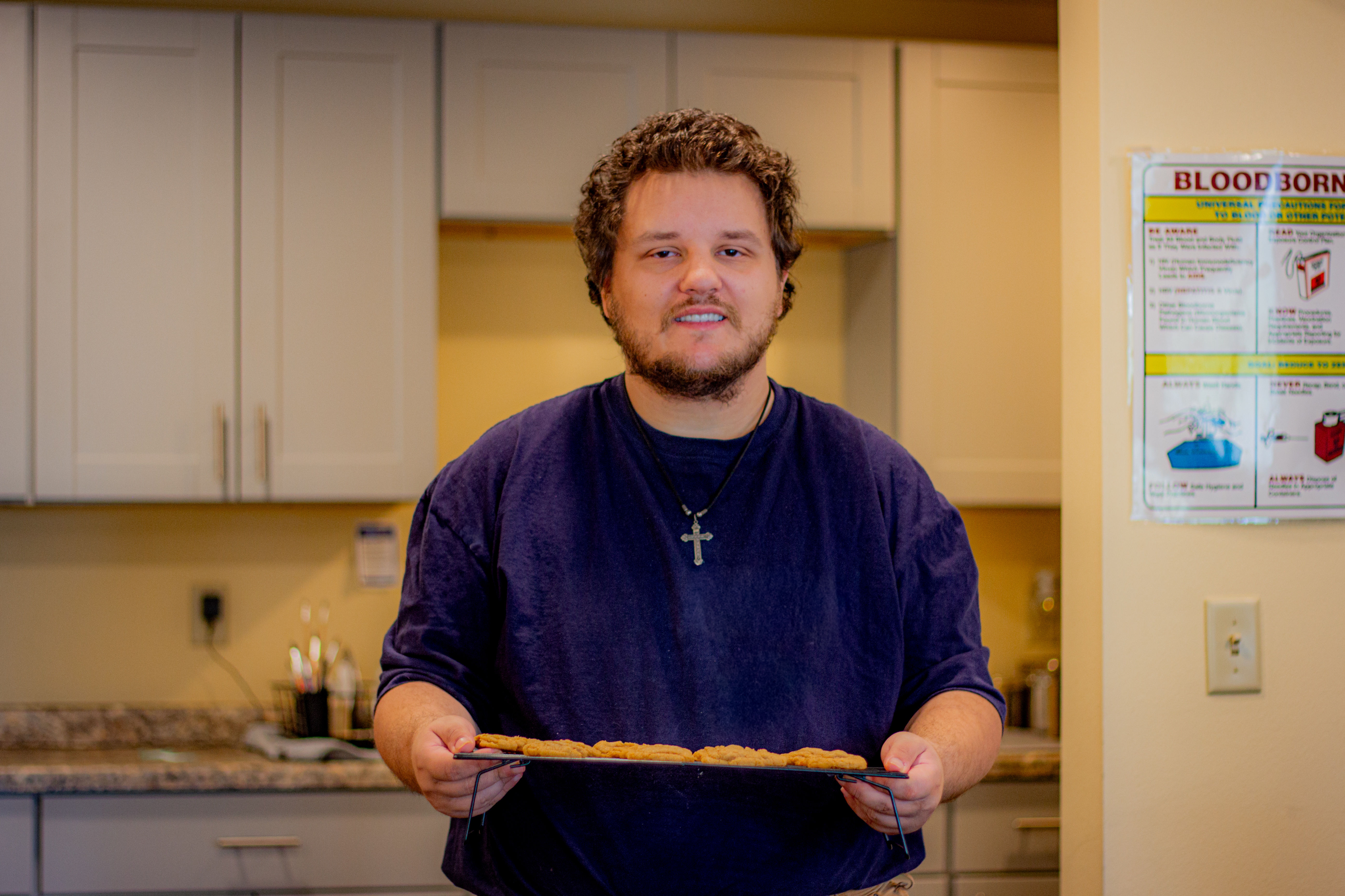A man posing with a freshly baked rack of cookies in Pathways' kitchen.