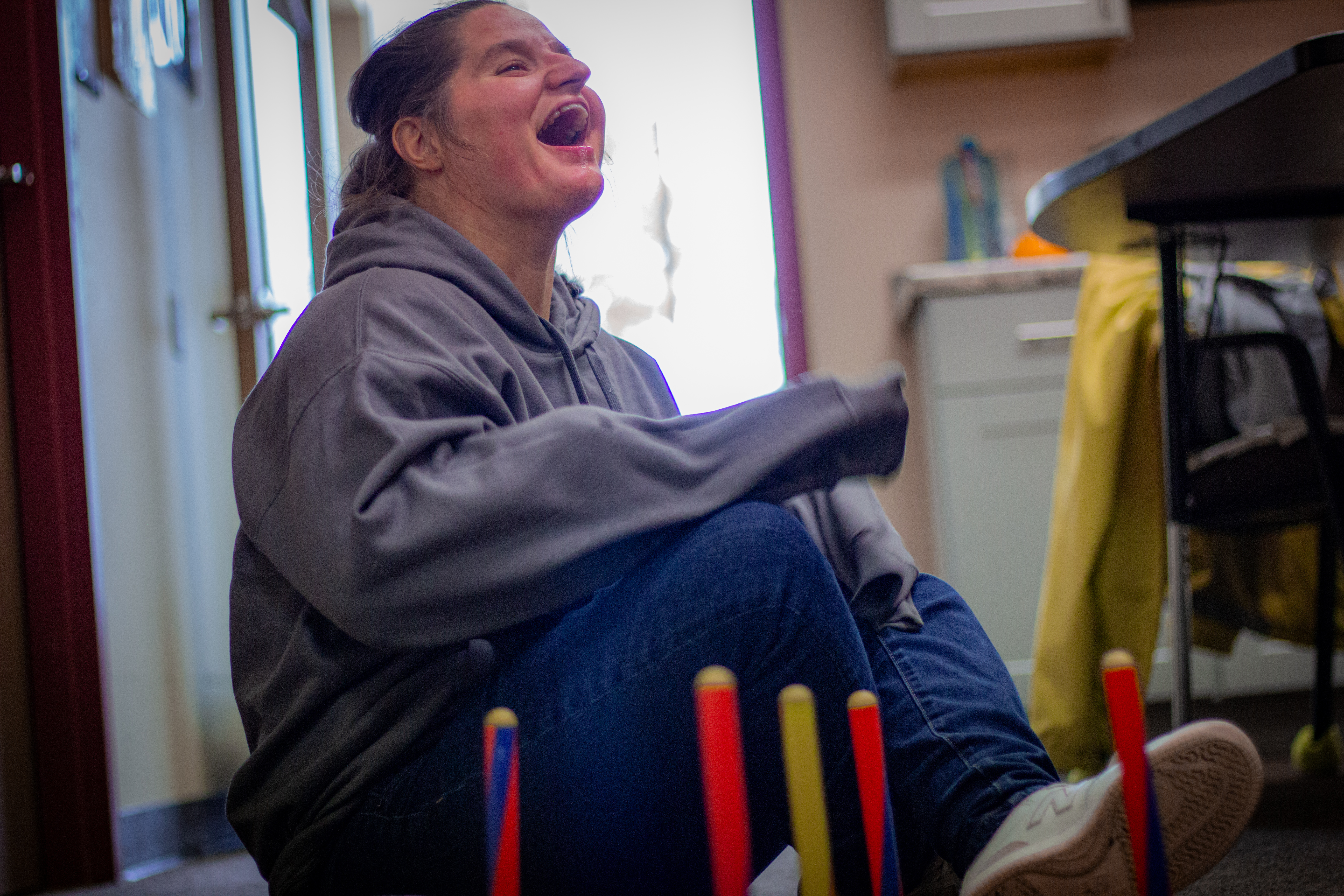 A woman laughing in front of colored rods.