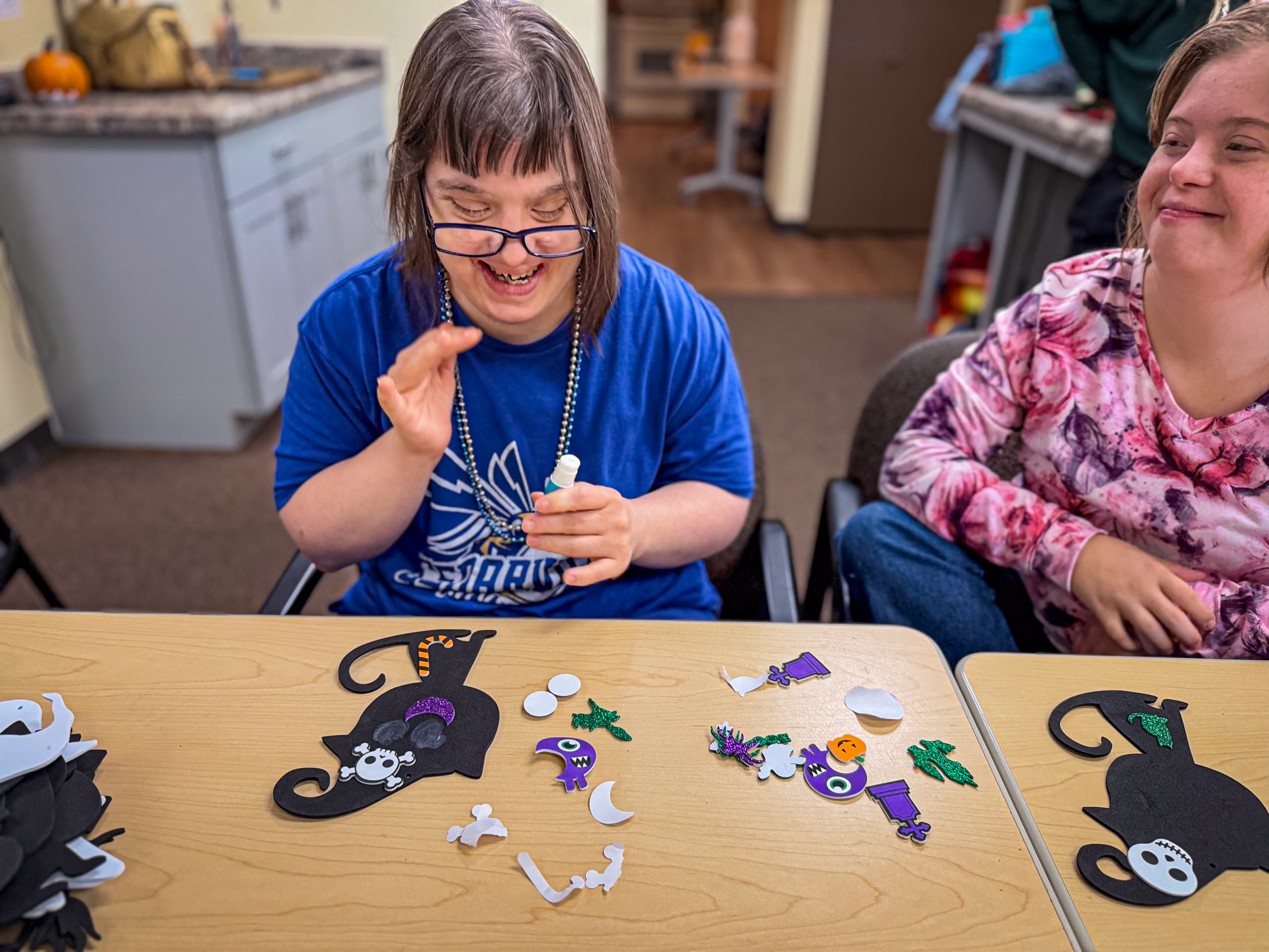 Two women sitting at a table completing an arts and crafts project.
