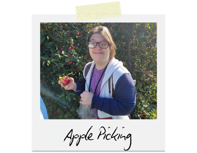 Apple Picking: A woman stands in front of an apple tree, holding a freshly picked apple.