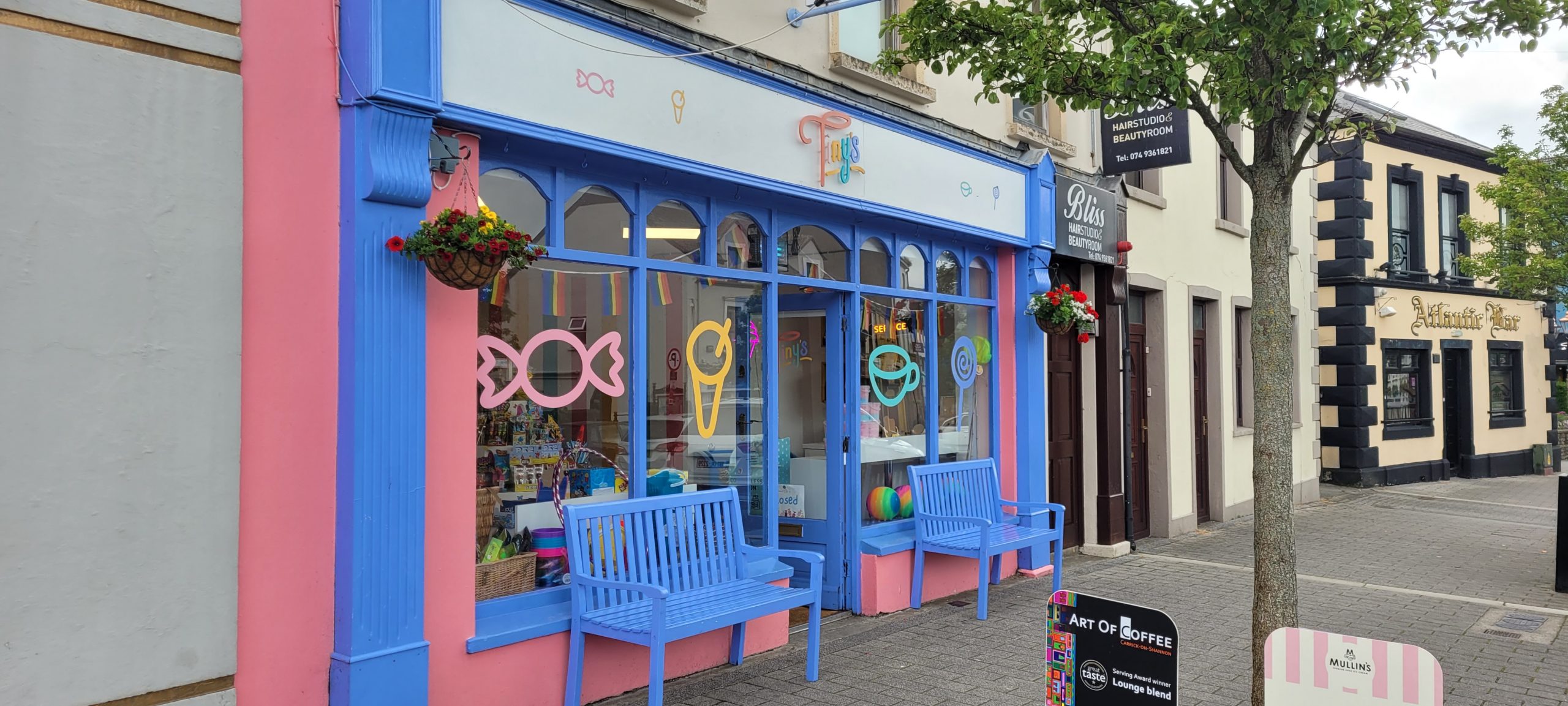 The colourful Tiny's shopfront with blue benches in Buncrana