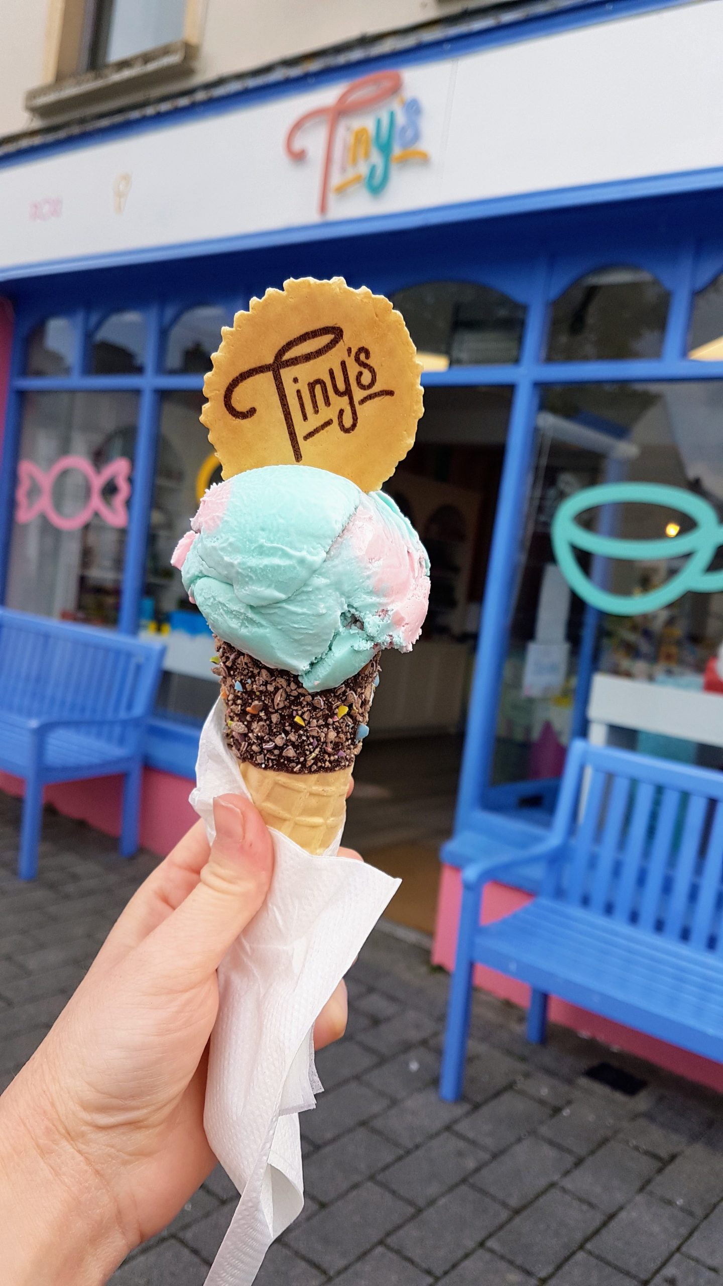 An ice cream cone held outside Tiny's with a branded wafer