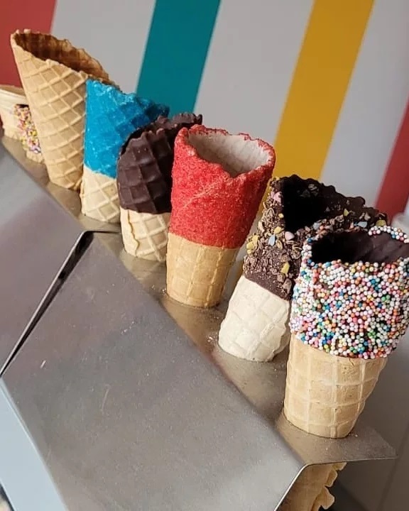 Decorated ice cream cones against the colourful shop wall at Tiny's