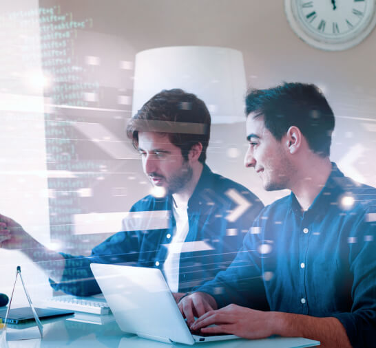 Two IT professionals collaborating on a laptop in a modern office, with digital code and data overlay representing technology and software development.