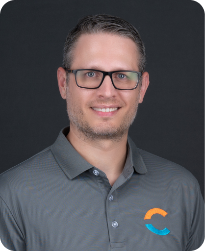 Professional headshot of Patrick Lahaie, wearing glasses and a gray polo shirt, smiling against a dark gray background.