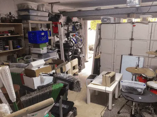 A messy, overflowing residential garage space filled with power tools and plastic bins.