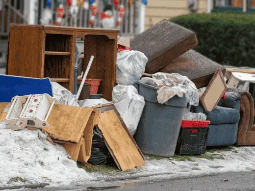 Heaps of discarded household items and trash left outside a rental home.