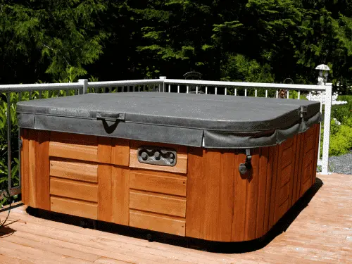 A large, unused wooden spa taking up space on a residential outdoor patio.