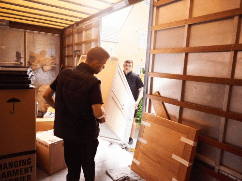 Workers lifting a heavy piece of discarded furniture into a commercial hauling van.