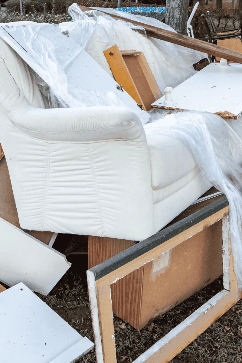 A messy outdoor scene with piles of discarded cardboard boxes and random bulky household junk waiting for pickup.