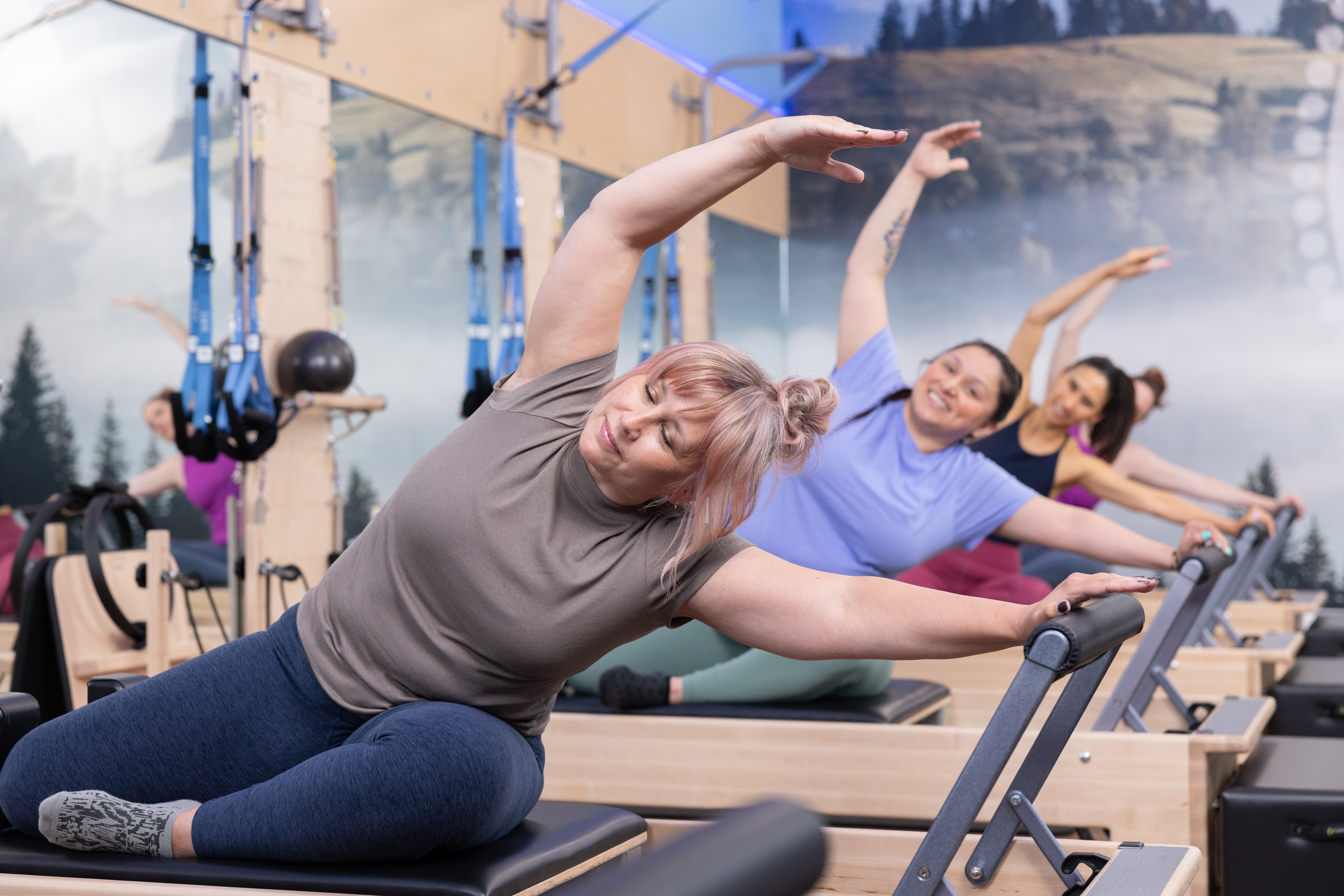 Club Pilates instructor guiding a member on a Reformer with care
