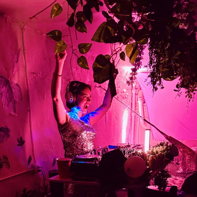 A DJ playing a set under pink lights
