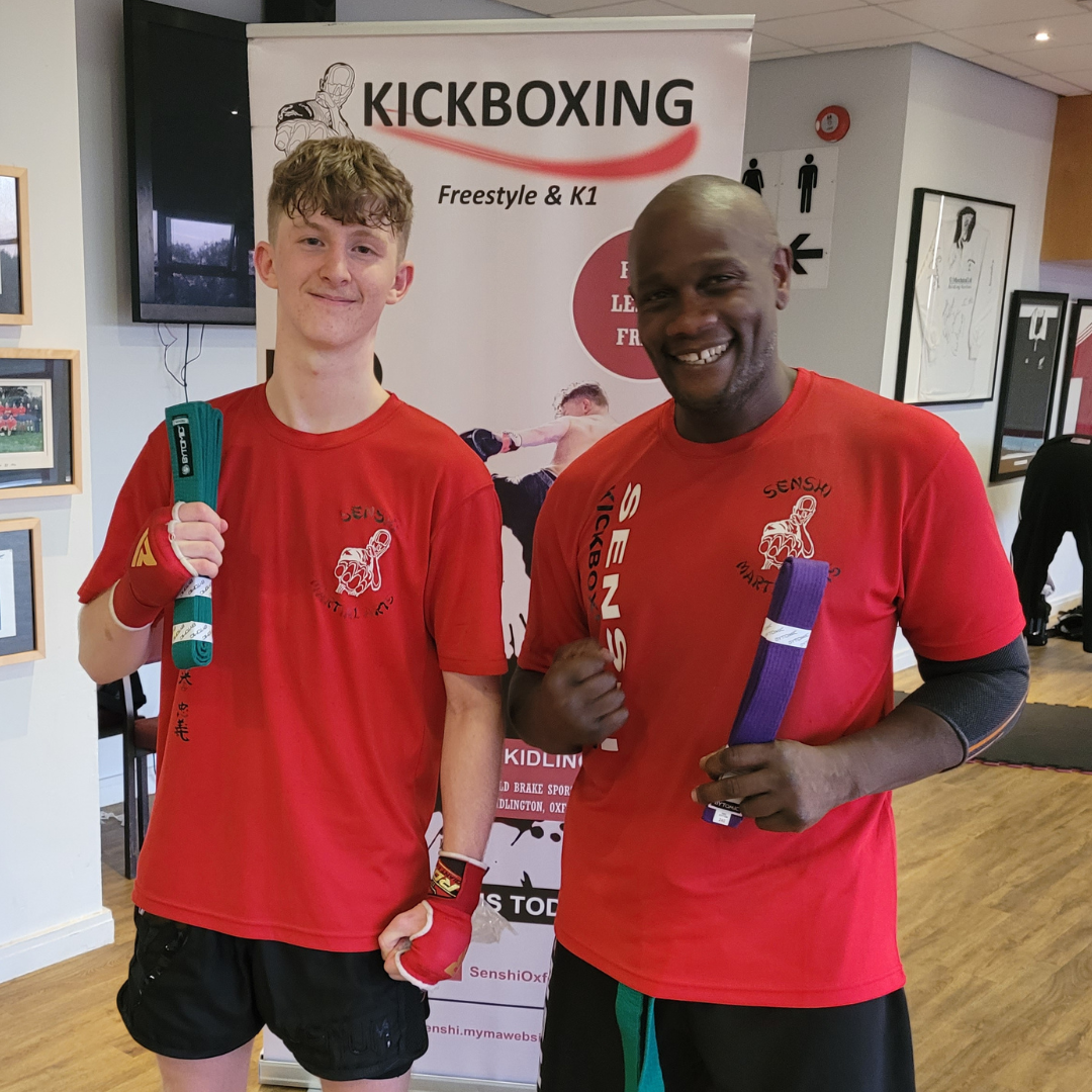 Senshi Martial Arts - Two adult Kickboxers smiling whilst holding their new belts after their successful grading.