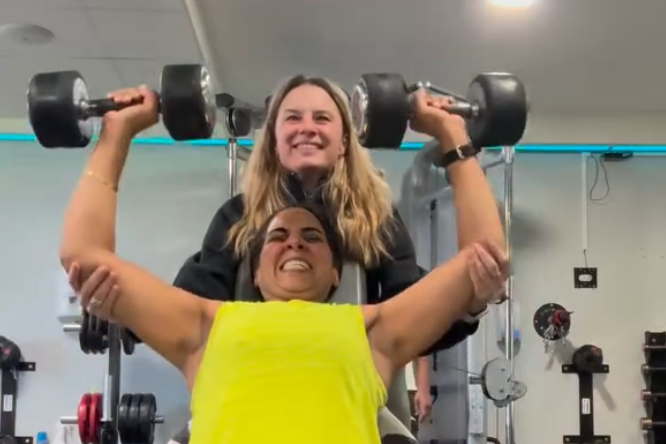 Kat spotting a client on a strength machine