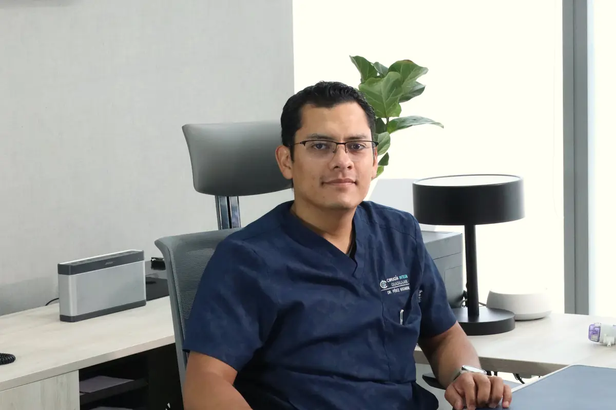 El Dr. Víctor Hugo Pérez Bocanegra con filipina azul marino, sentado en el escritorio de su consultorio