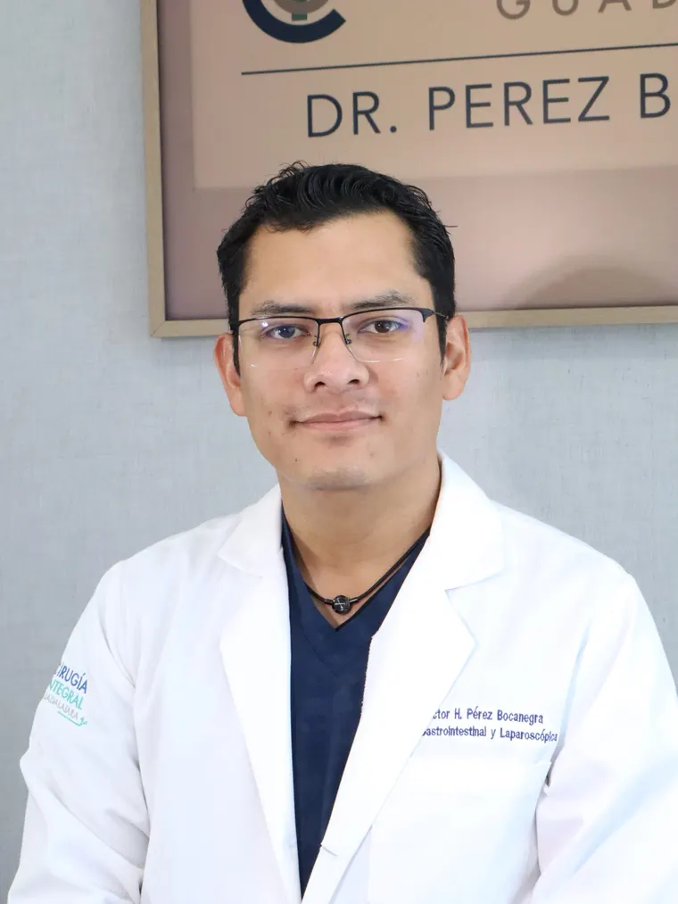 El Dr. Víctor Hugo Pérez Bocanegra con bata frente al letrero de su consultorio
