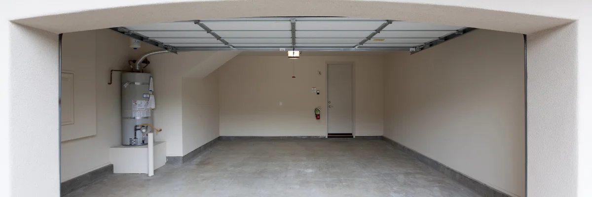 Empty residential garage with water heater and open garage door.