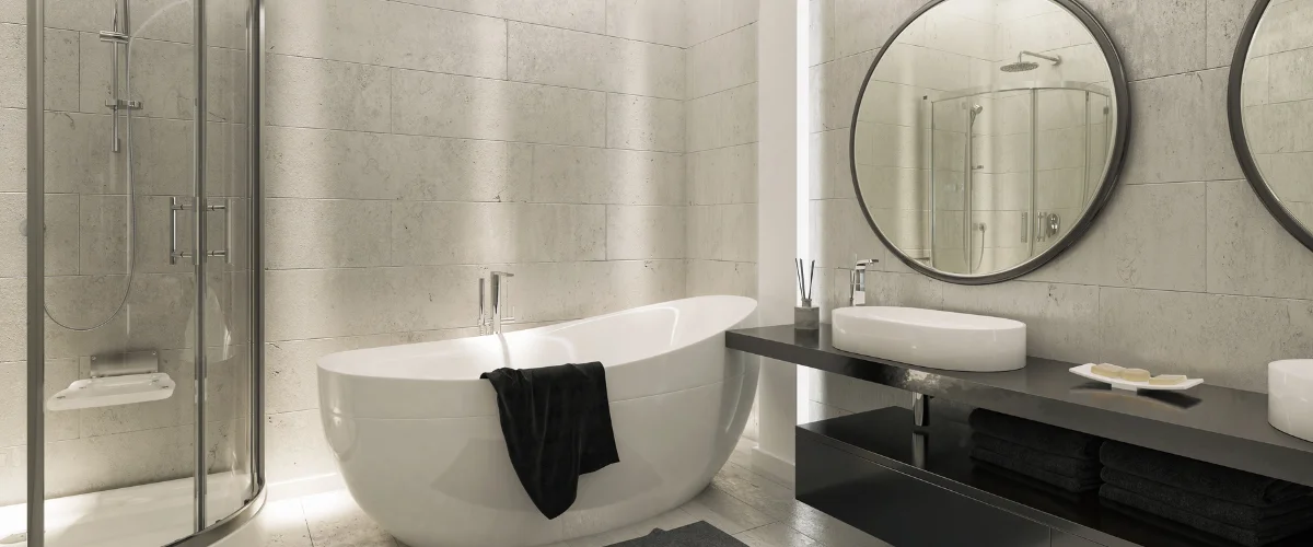 A modern bathroom with a freestanding white tub, shower, dark vanity with two sinks, and two round mirrors.