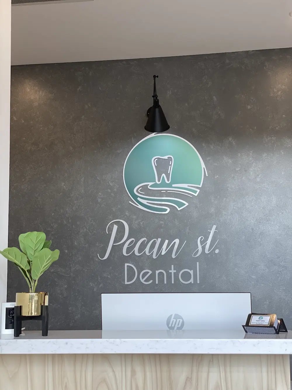 Front desk and logo wall at Pecan St. Dental