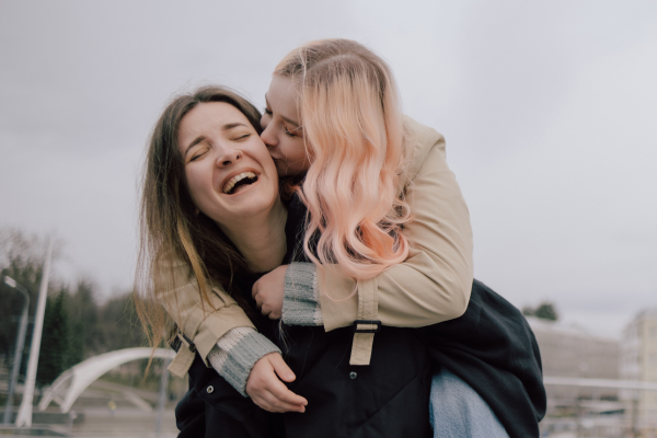 lesbian giving her girlfriend a piggyback ride and earning a peck on the cheek