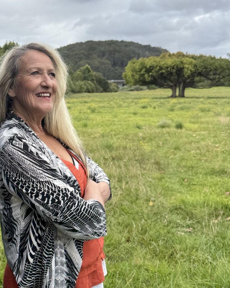 Nadine smiling in a green paddock, in a black and white jacket