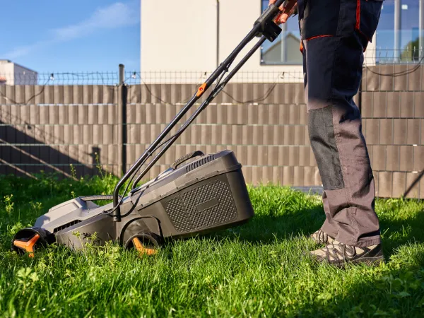 Professional performing lawn mowing as part of regular yard maintenance.