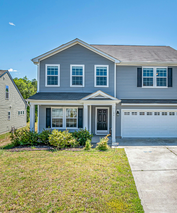 Front yard of a suburban home with trimmed bushes and maintained lawn.