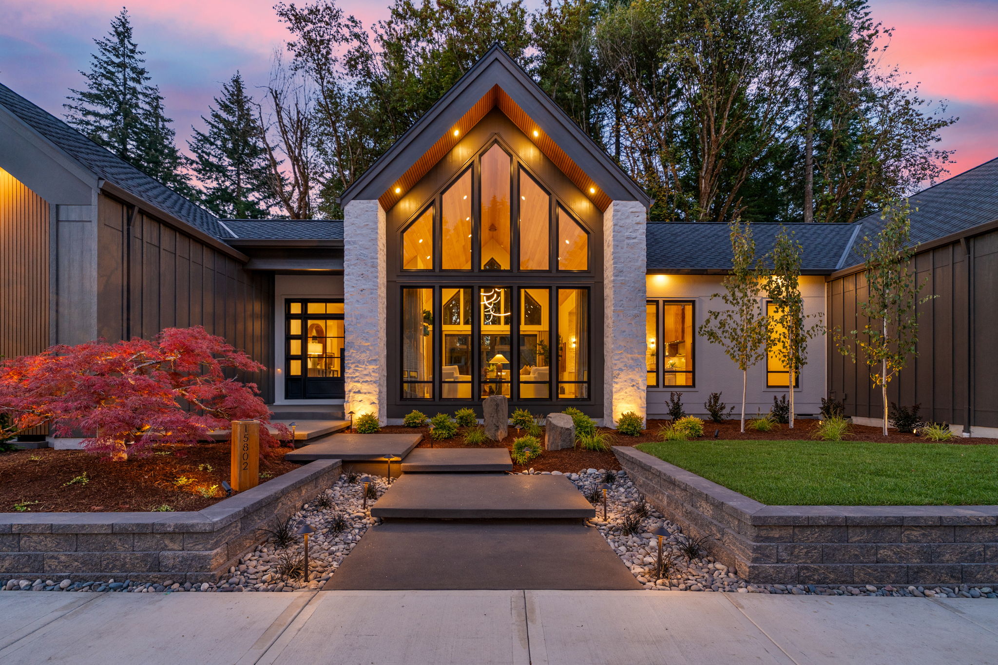 Modern home illuminated at twilight with pink sky