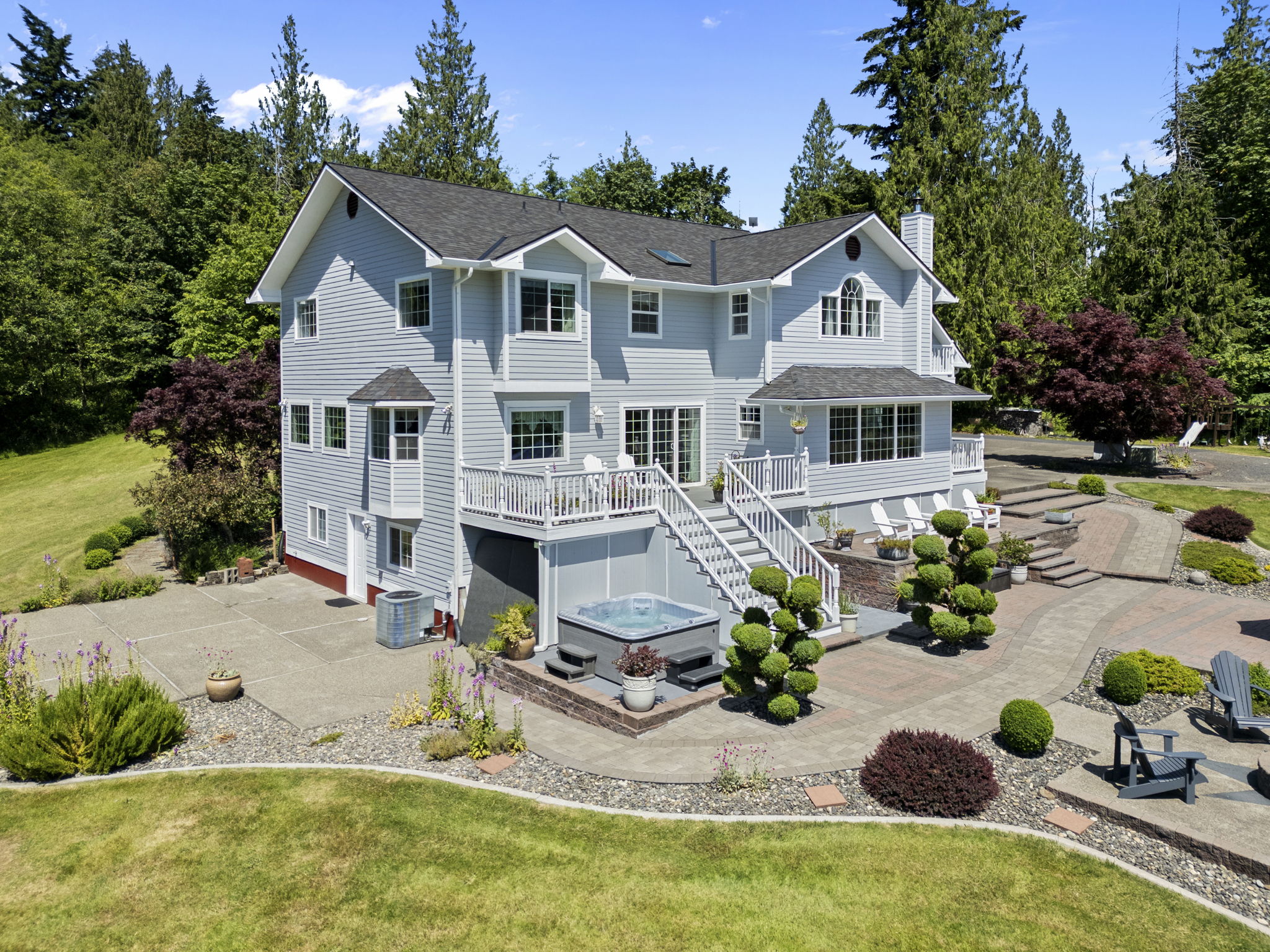 Aerial view of a white home and landscaped yard