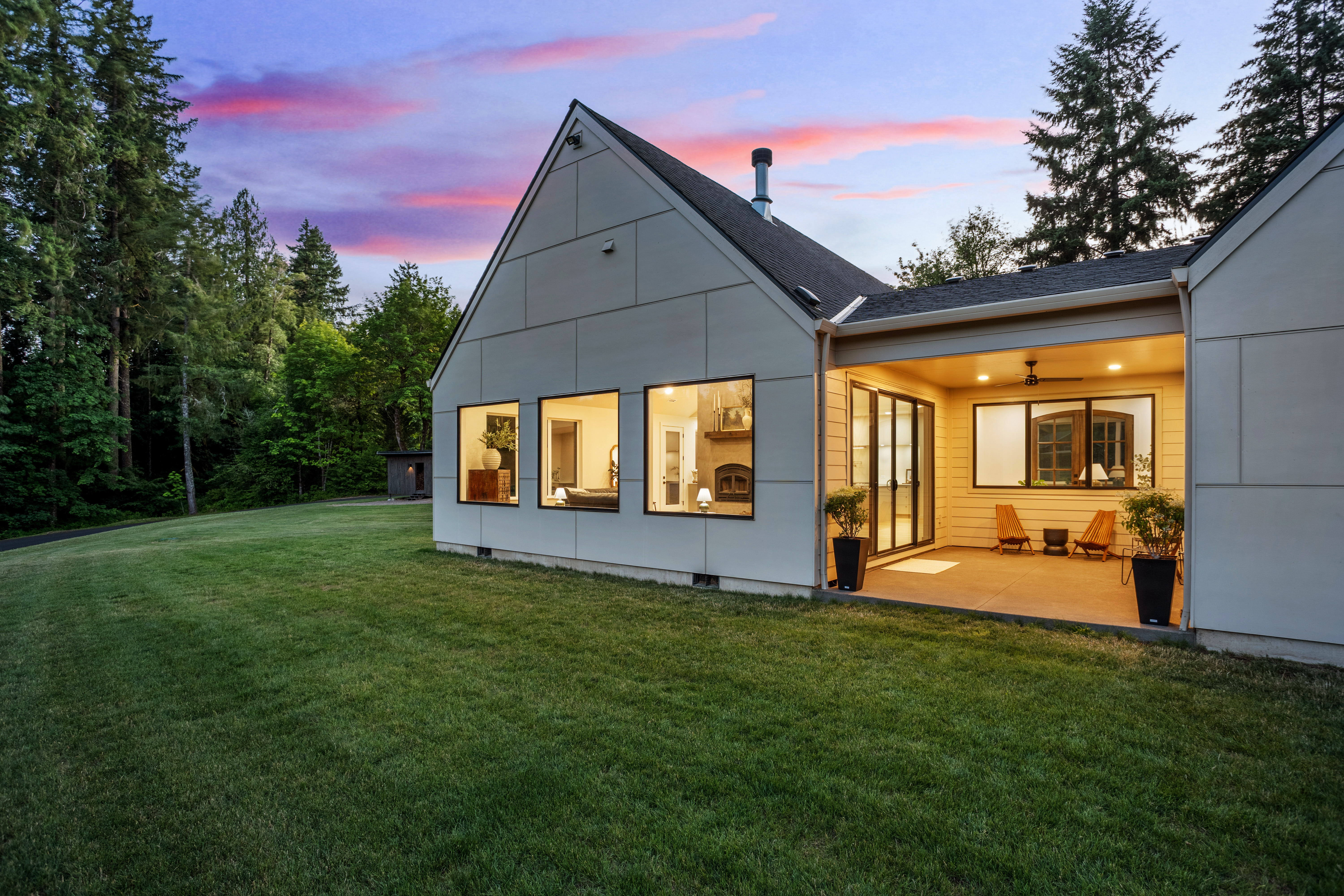 Angled backyard view of a home beneath a pink twilight sky