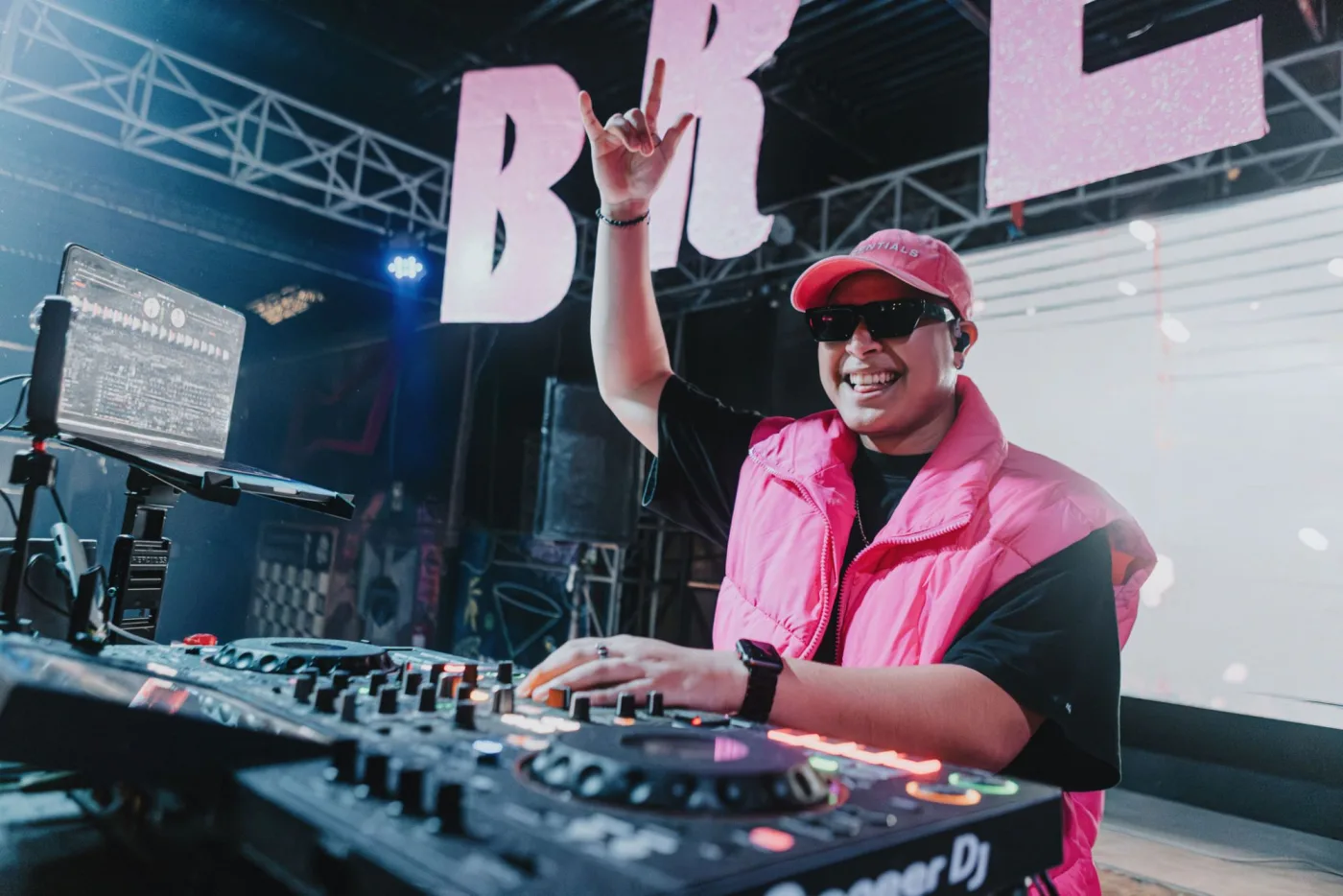 NOLAH detr√°s de la consola, sonriendo y con la mano en alto